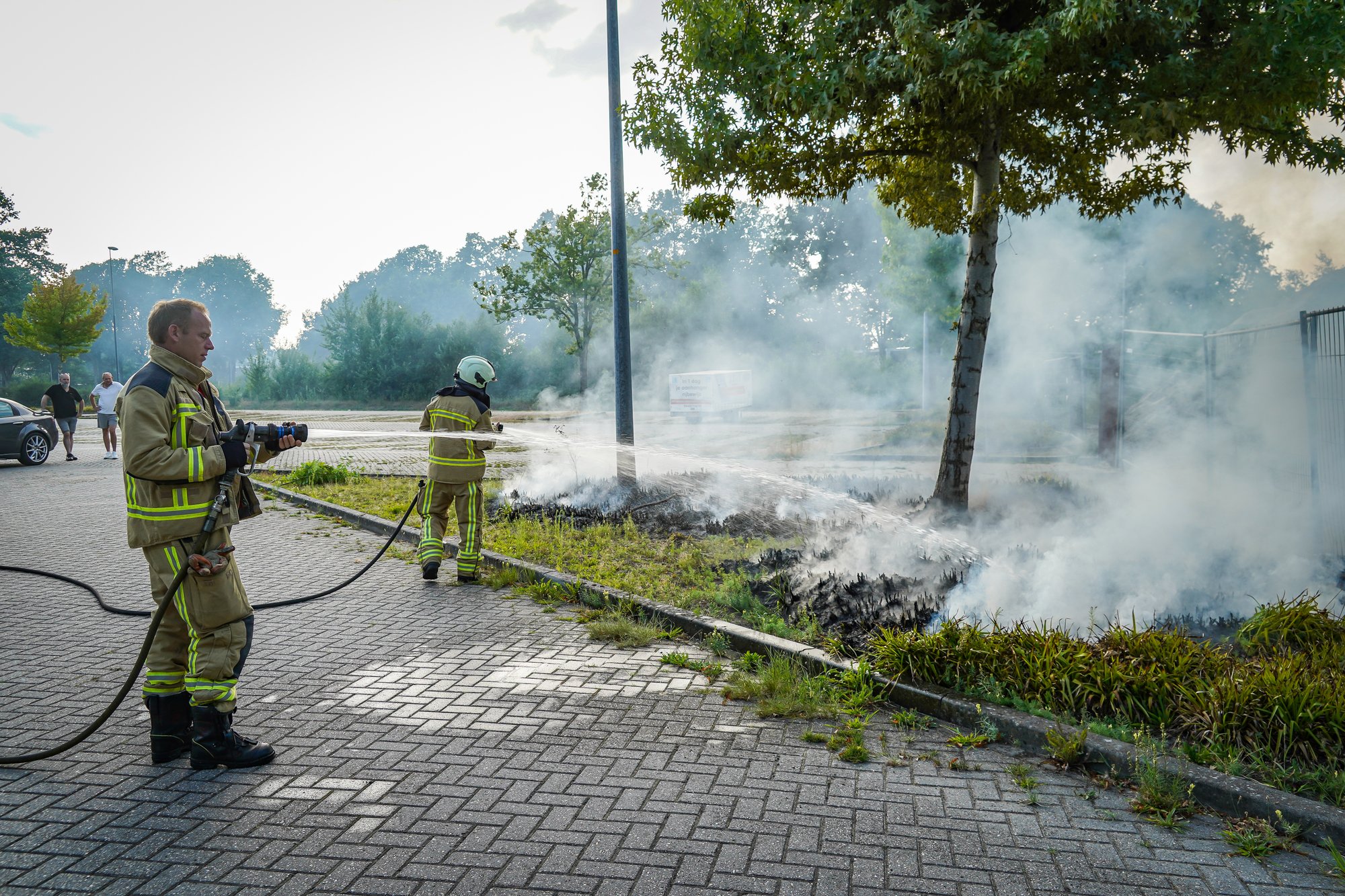 Bosjes bij parkeerplaats in brand aan de Sint Gerardusstraat in Emmen, forse rookontwikkeling zichtbaar