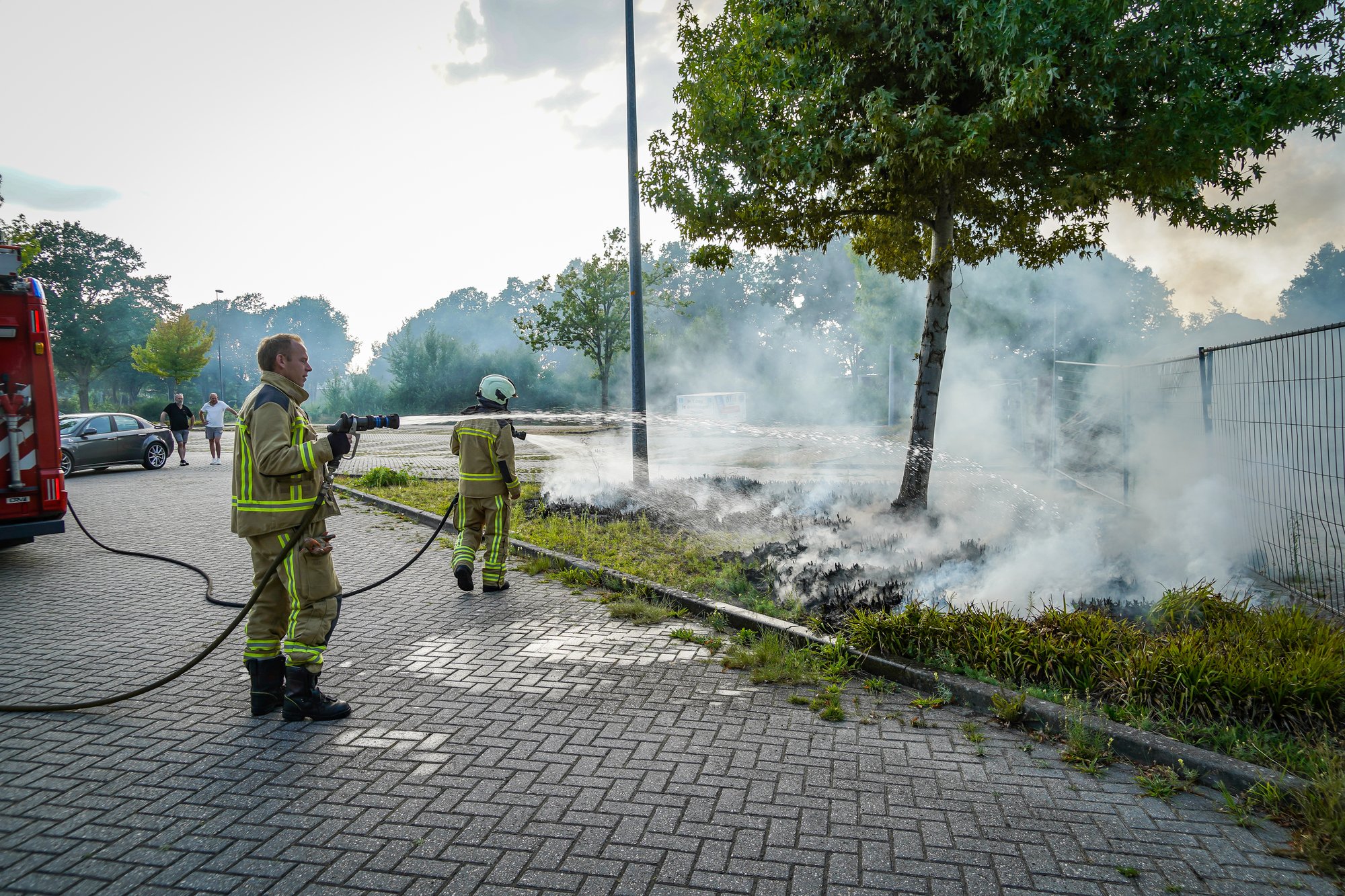 Bosjes bij parkeerplaats in brand aan de Sint Gerardusstraat in Emmen, forse rookontwikkeling zichtbaar
