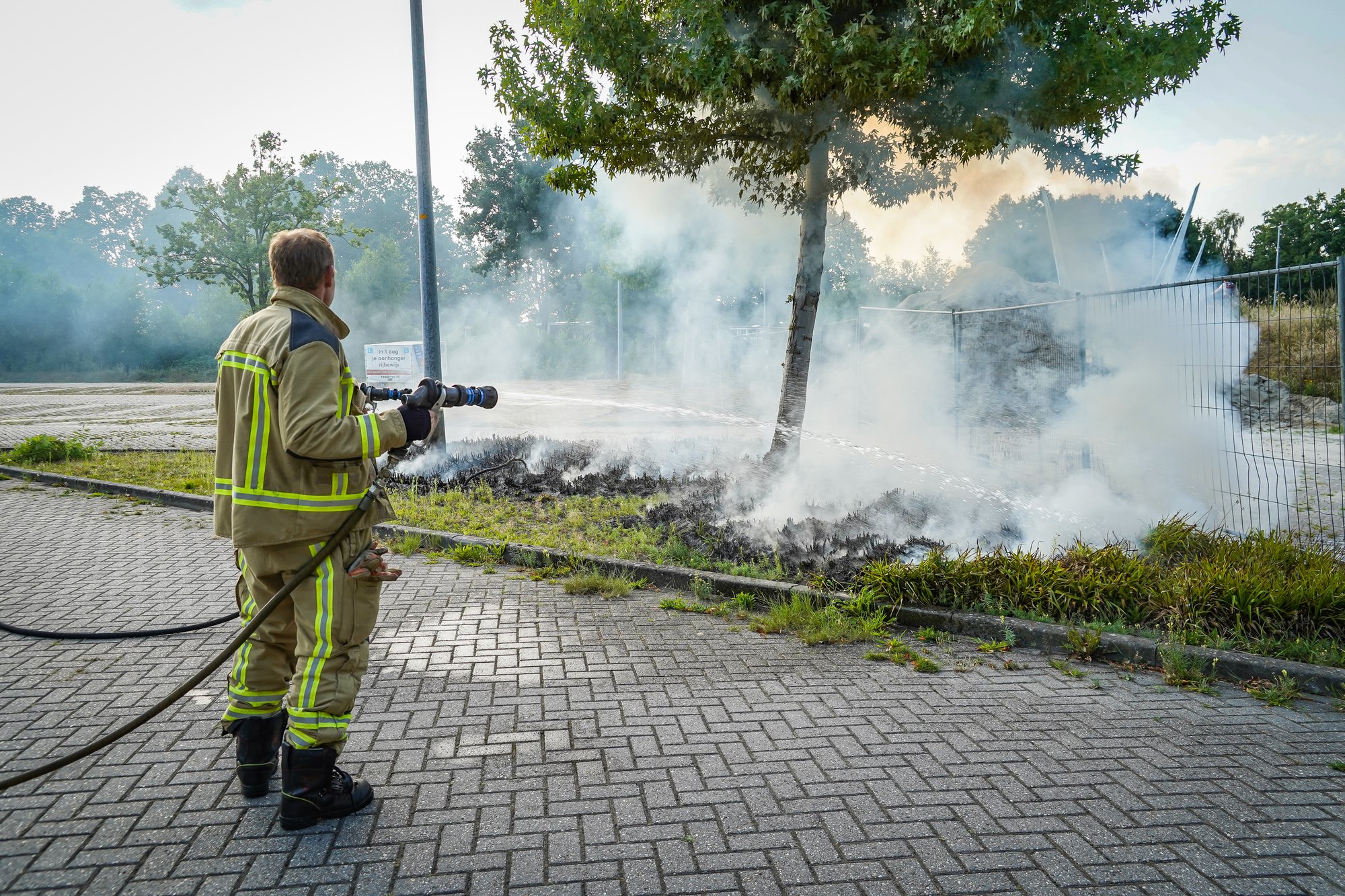 Bosjes bij parkeerplaats in brand aan de Sint Gerardusstraat in Emmen, forse rookontwikkeling zichtbaar
