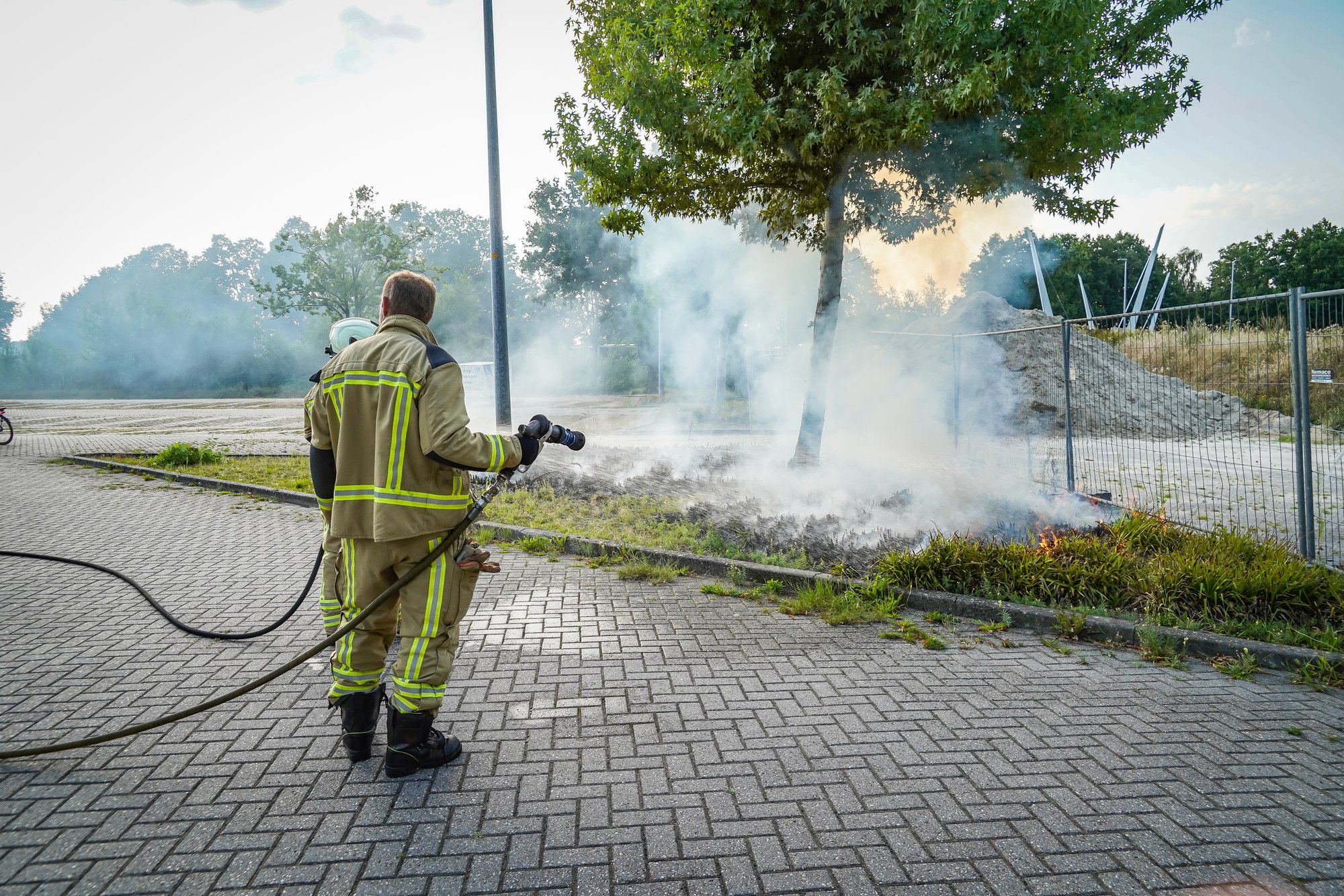 Bosjes bij parkeerplaats in brand aan de Sint Gerardusstraat in Emmen, forse rookontwikkeling zichtbaar