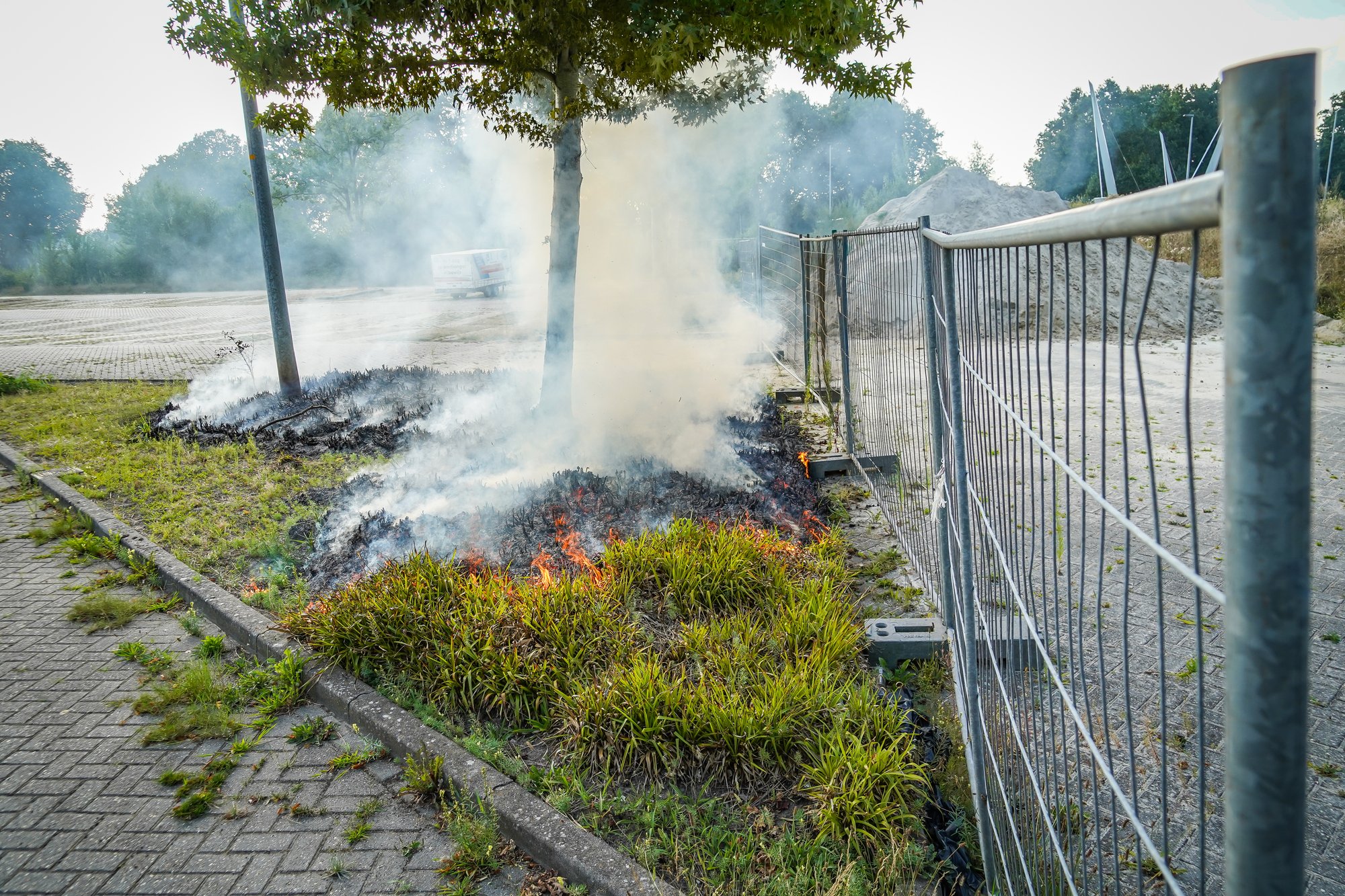 Bosjes bij parkeerplaats in brand aan de Sint Gerardusstraat in Emmen, forse rookontwikkeling zichtbaar