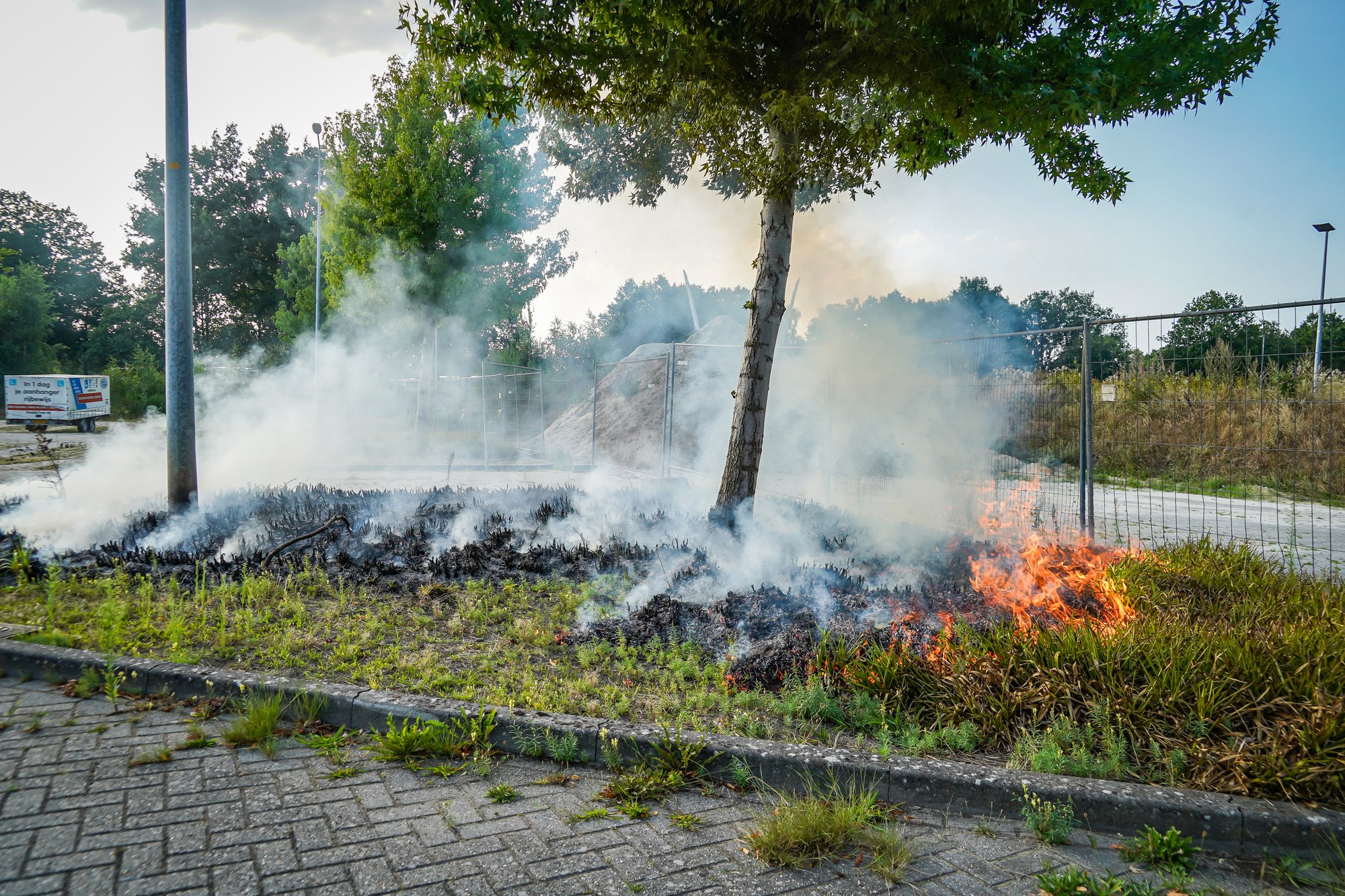 Bosjes bij parkeerplaats in brand aan de Sint Gerardusstraat in Emmen, forse rookontwikkeling zichtbaar