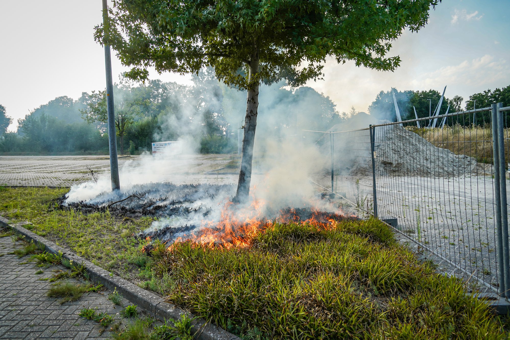 Bosjes bij parkeerplaats in brand aan de Sint Gerardusstraat in Emmen, forse rookontwikkeling zichtbaar